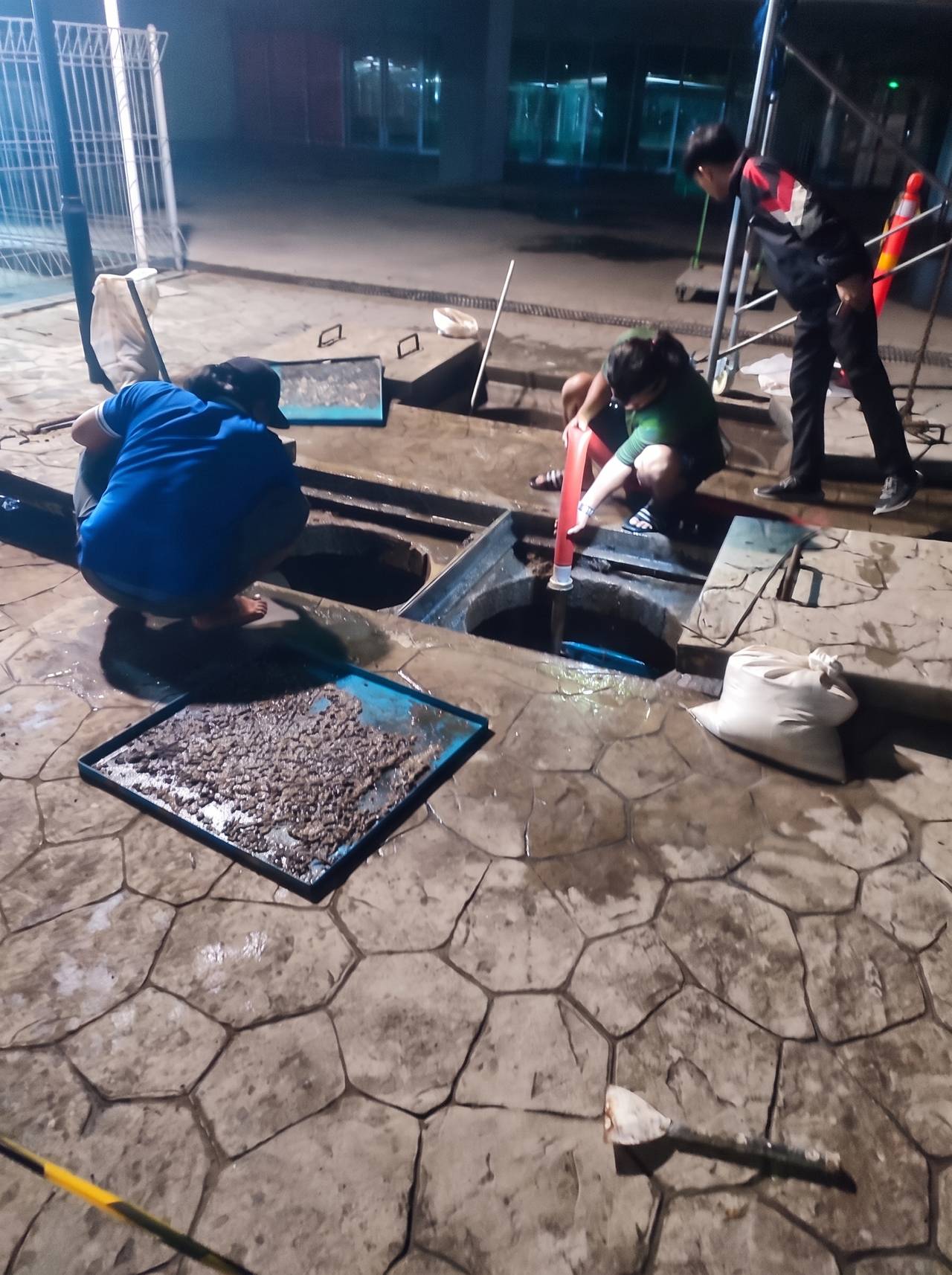 Tim teknisi menguras bak kontrol saluran luar pada pengerjaan malam hari