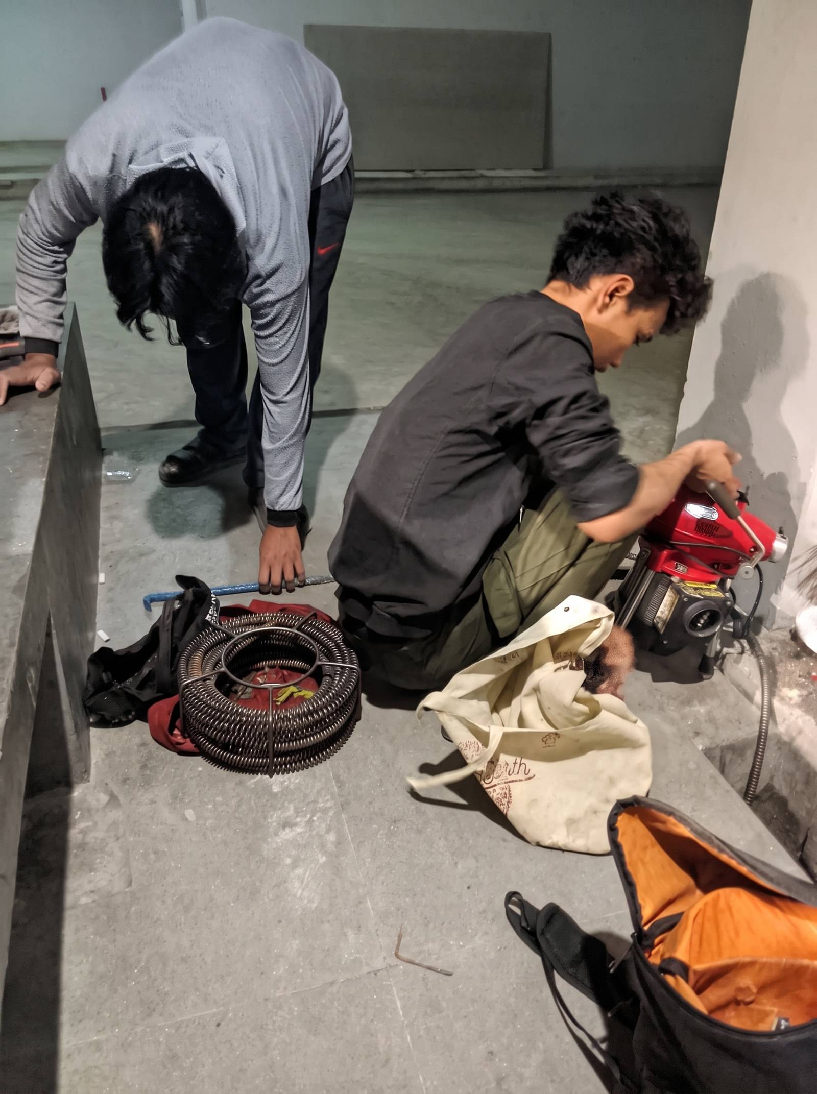 Dua teknisi Banyu Lancar mengoperasikan mesin spiral drain cleaner di lokasi